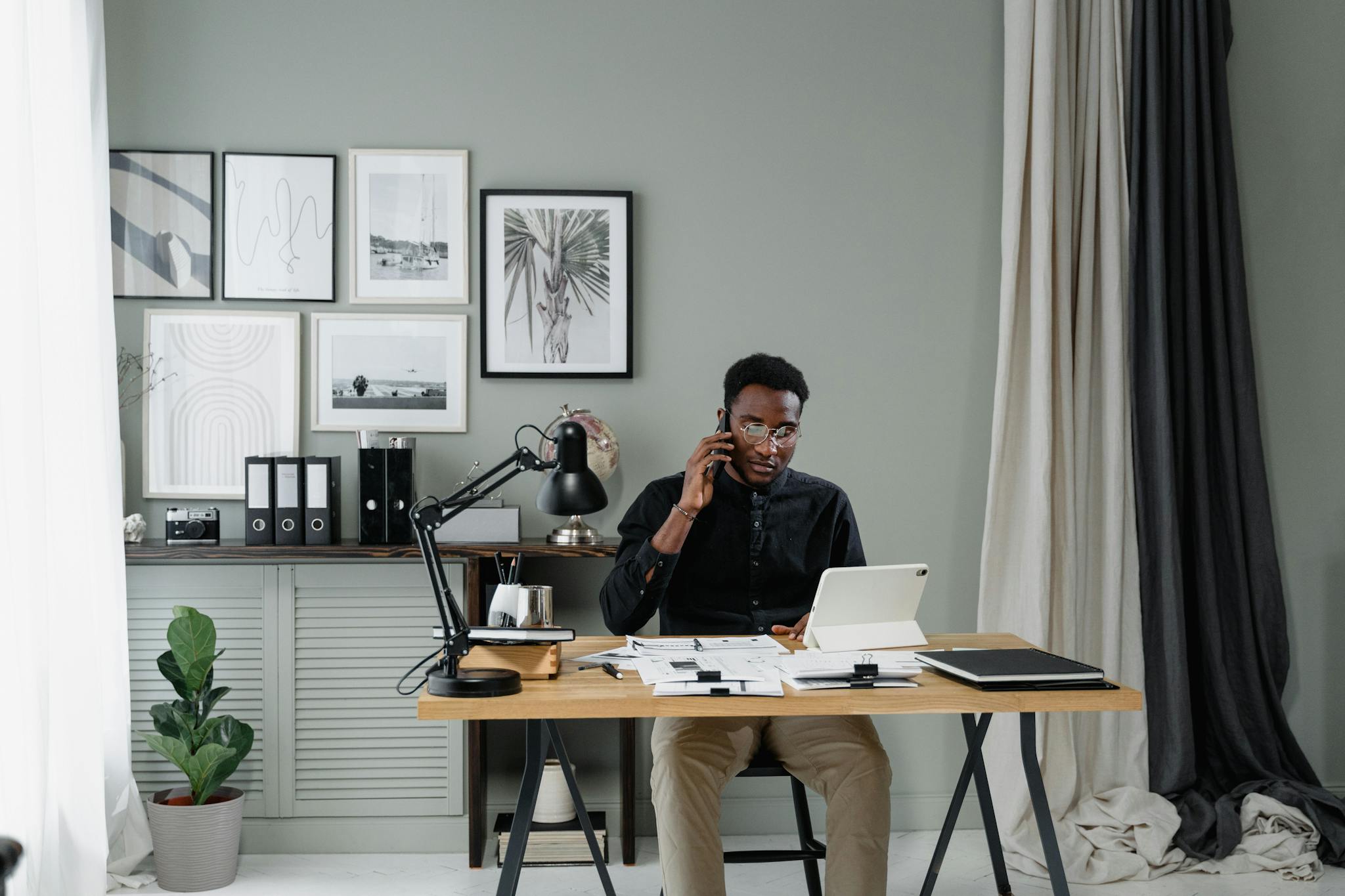 Businessman talking on phone while working in stylish office with tablet and documents.